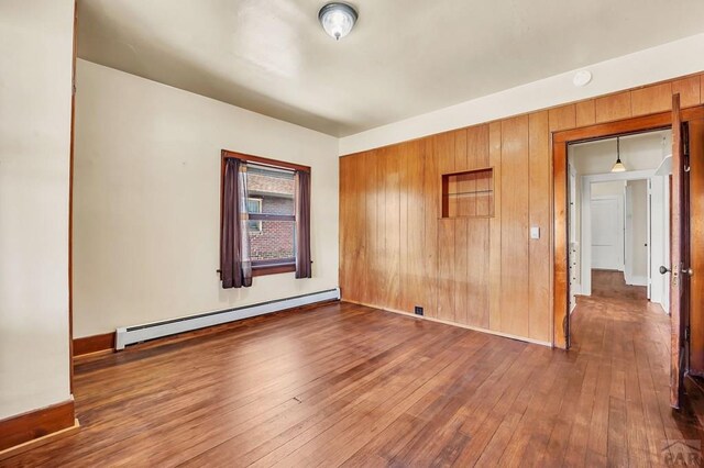 empty room with a baseboard heating unit and dark wood-style flooring