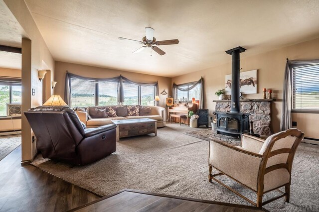 living room with a wealth of natural light, dark wood-type flooring, and a wood stove