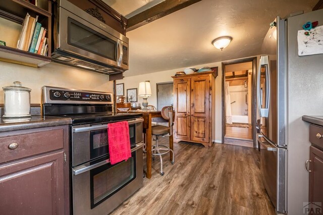 kitchen featuring stainless steel appliances, dark countertops, and wood finished floors