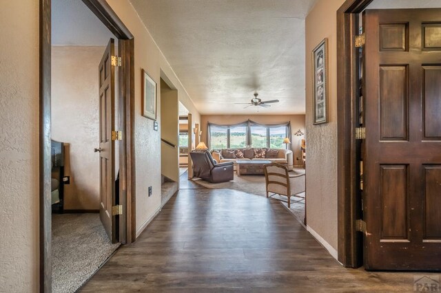 hall with dark wood-style floors, baseboards, and a textured wall