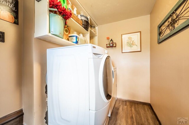 laundry room with dark wood-type flooring, laundry area, baseboards, and washing machine and clothes dryer