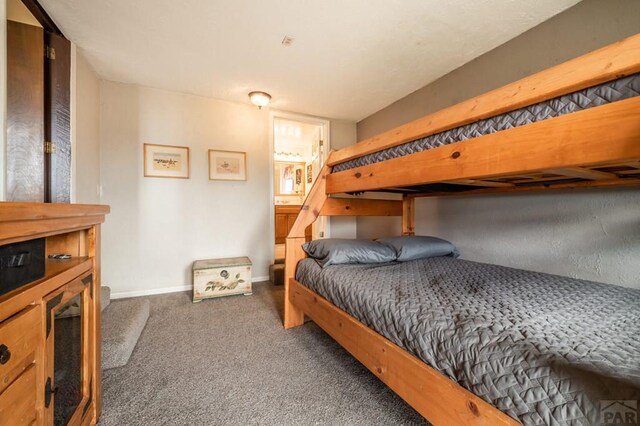 bedroom featuring dark colored carpet and baseboards