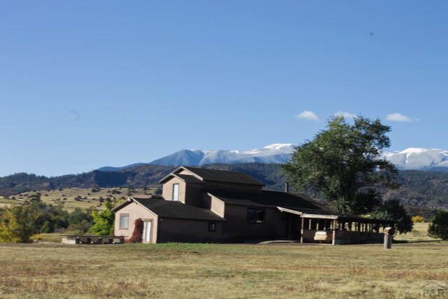 view of side of property featuring a yard, a rural view, and a mountain view