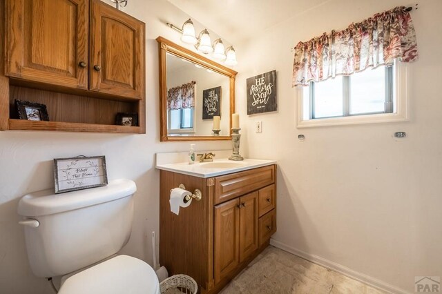 bathroom with toilet, baseboards, and vanity