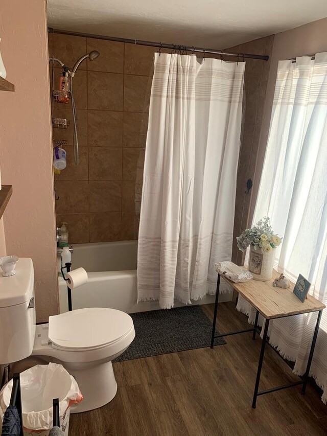 bathroom with shower / bath combination with curtain, toilet, and wood finished floors