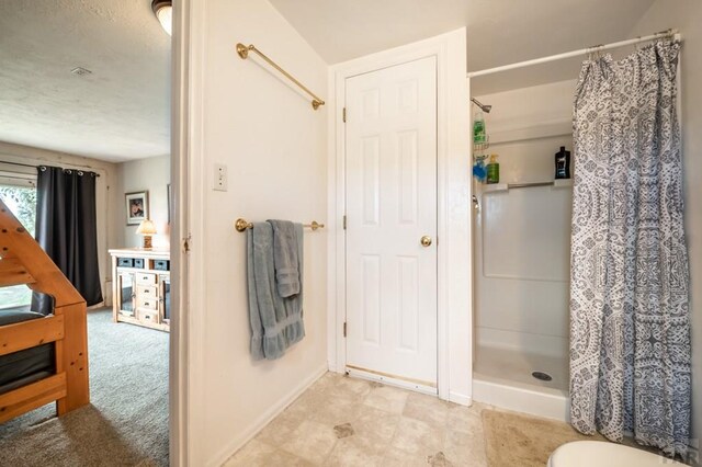 bathroom with a textured ceiling, a stall shower, and baseboards