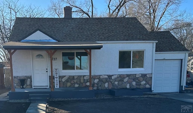 view of front of house with stone siding, a porch, a chimney, and stucco siding