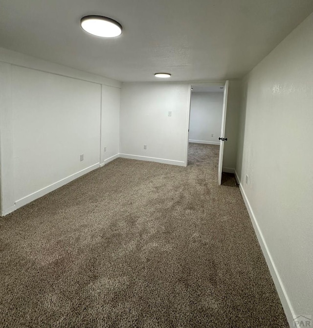 below grade area featuring baseboards and dark carpet