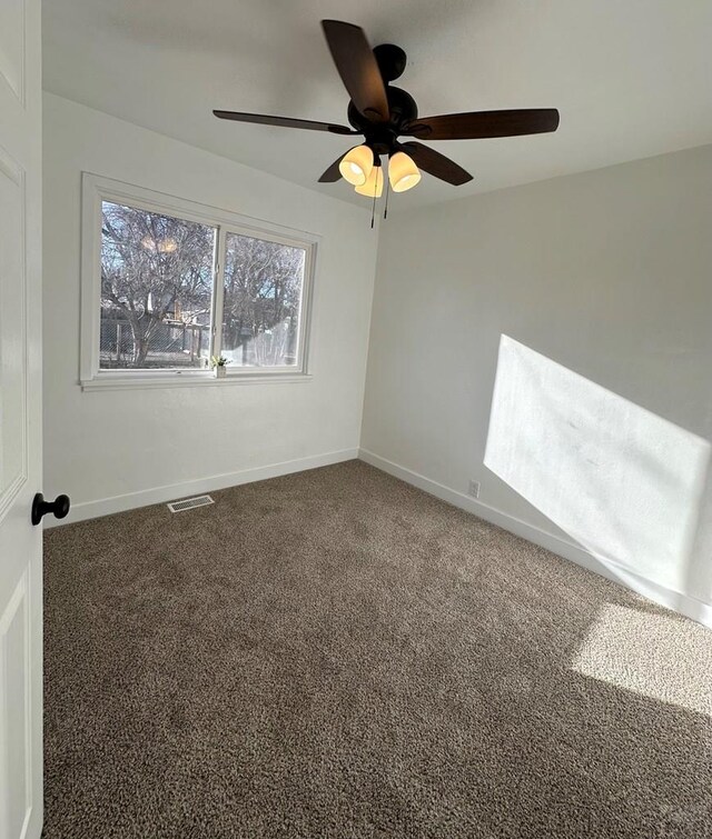 carpeted spare room featuring baseboards, visible vents, and a ceiling fan