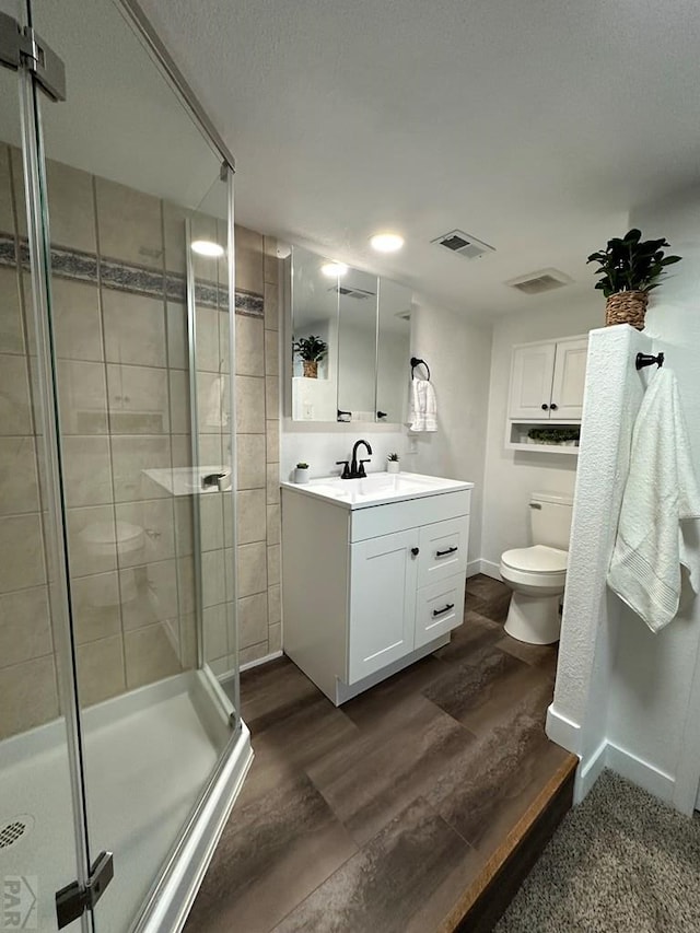 full bath with a stall shower, visible vents, toilet, wood finished floors, and vanity