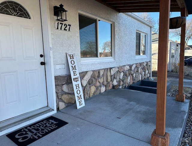 doorway to property featuring stone siding and stucco siding