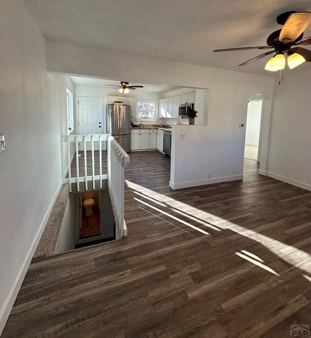 staircase with baseboards, a textured ceiling, arched walkways, and wood finished floors