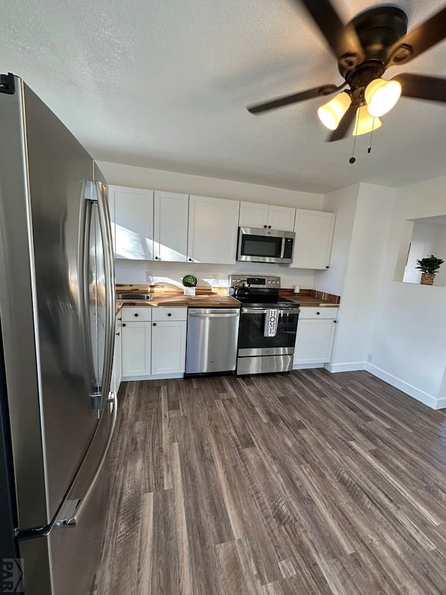 kitchen featuring stainless steel appliances, white cabinetry, wood counters, and dark wood-style floors