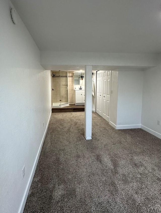 finished basement featuring baseboards and dark colored carpet