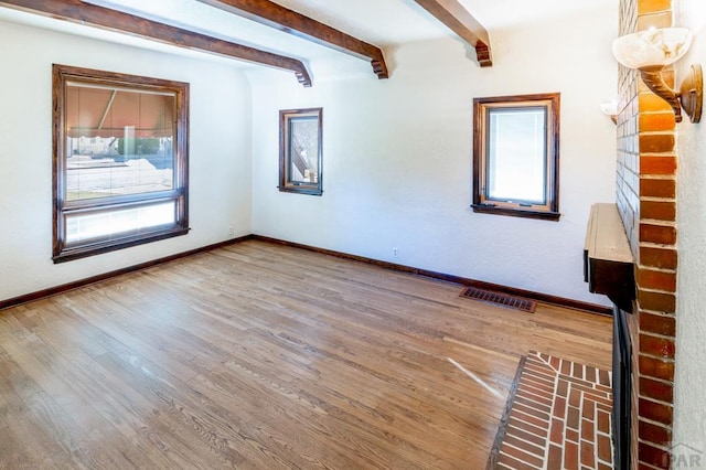 spare room featuring baseboards, visible vents, a wealth of natural light, and wood finished floors