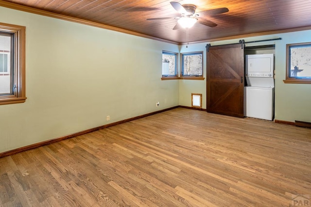 unfurnished bedroom featuring ornamental molding, a barn door, stacked washer / dryer, and wooden ceiling