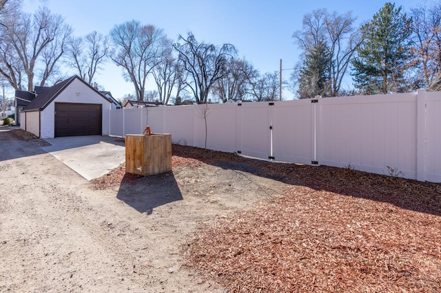 view of yard featuring concrete driveway, an outdoor structure, and fence