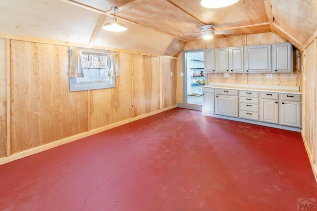 interior space featuring vaulted ceiling, baseboards, and wooden walls