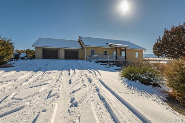 ranch-style house featuring covered porch, an attached garage, and stucco siding