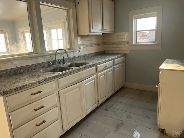 kitchen with dark countertops, plenty of natural light, backsplash, and a sink