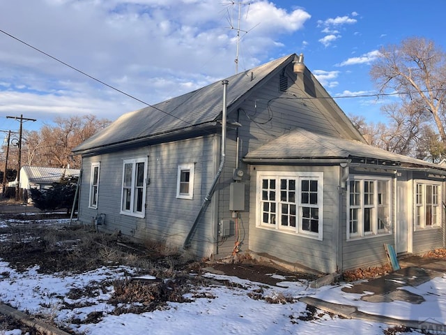 snow covered property featuring roof with shingles