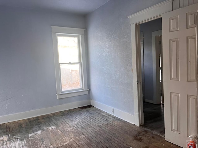 spare room with baseboards, hardwood / wood-style floors, and a textured wall