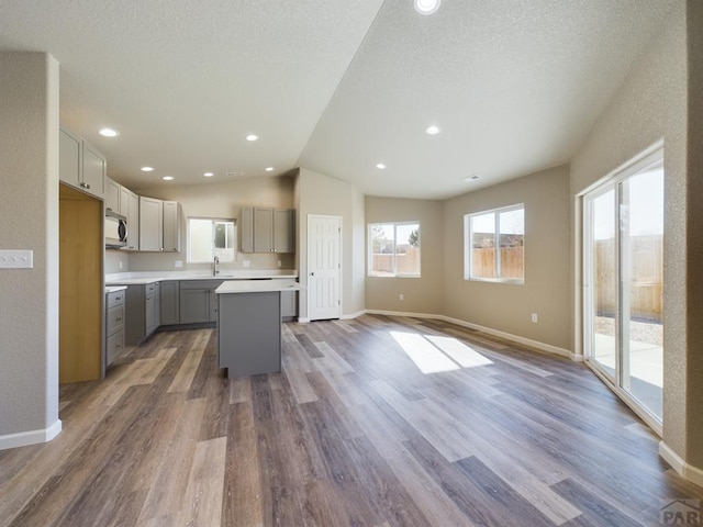 151 S Stardust Cir, Pueblo West, CO 81007 - kitchen with a center island, wood finished floors, stainless steel microwave, a sink, and gray cabinetry