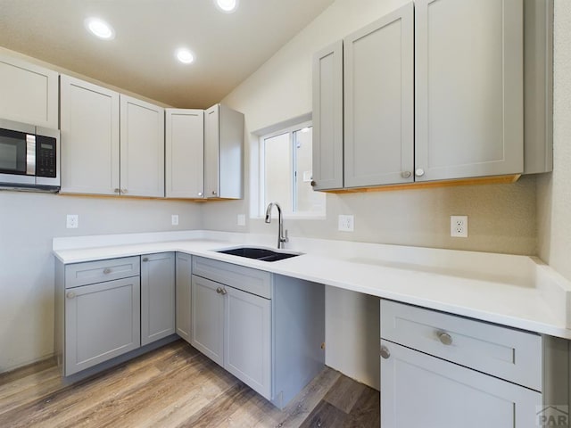 151 S Stardust Cir, Pueblo West, CO 81007 - kitchen with light wood-style flooring, recessed lighting, gray cabinets, stainless steel microwave, and a sink