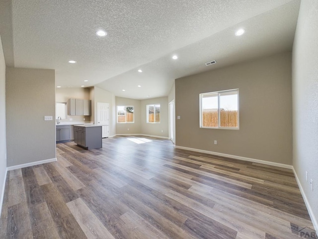 151 S Stardust Cir, Pueblo West, CO 81007 - unfurnished living room with baseboards, vaulted ceiling, recessed lighting, a textured ceiling, and wood finished floors