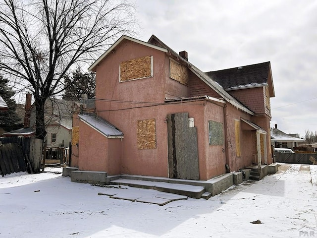 exterior space featuring fence, a chimney, and stucco siding