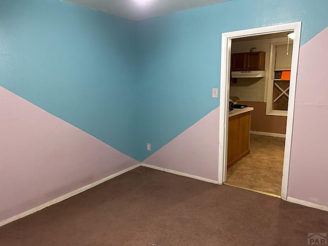 unfurnished room featuring baseboards and dark carpet