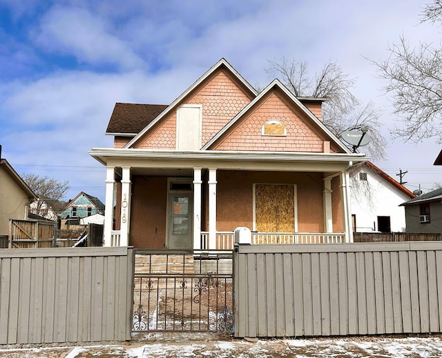 view of front of home featuring covered porch, a fenced front yard, a gate, and stucco siding