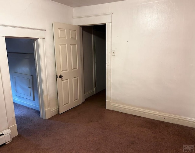 unfurnished room featuring dark colored carpet, a baseboard radiator, and baseboards