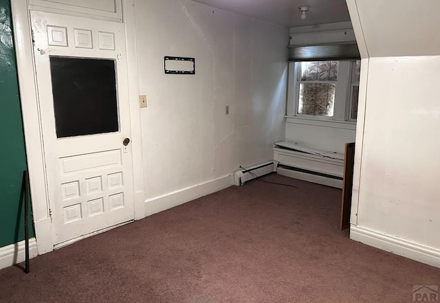 spare room featuring a baseboard radiator, baseboards, and dark colored carpet