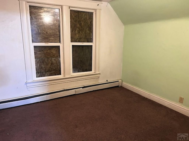 unfurnished room with vaulted ceiling, dark colored carpet, baseboard heating, and baseboards