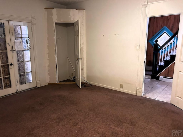 unfurnished room featuring a baseboard radiator, light tile patterned flooring, light colored carpet, stairs, and french doors