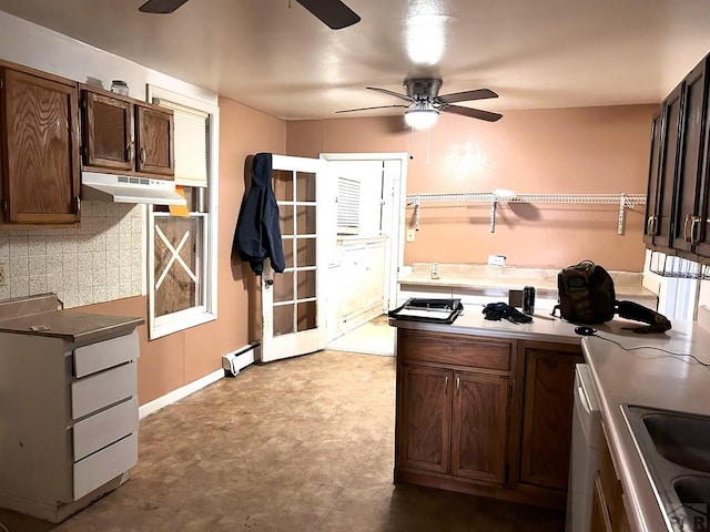 kitchen with tasteful backsplash, a baseboard radiator, a ceiling fan, dark brown cabinets, and under cabinet range hood