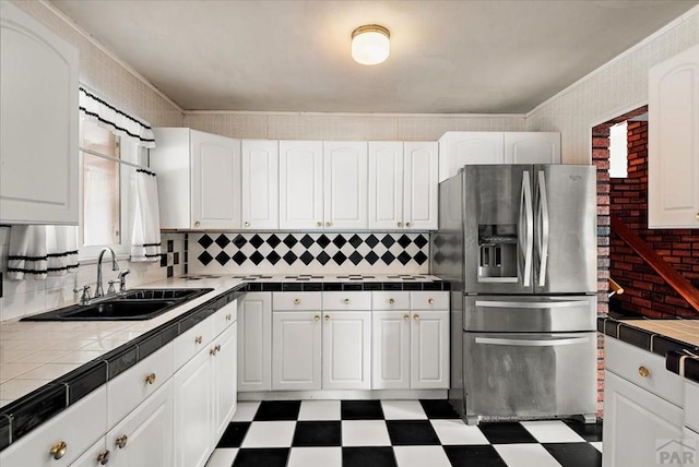 kitchen with tile counters, white cabinets, dark floors, stainless steel refrigerator with ice dispenser, and a sink