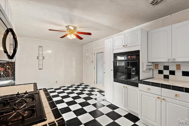 kitchen featuring dark floors, oven, white cabinetry, and tile countertops