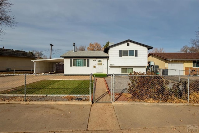 split level home with driveway, a fenced front yard, a gate, a carport, and a front yard