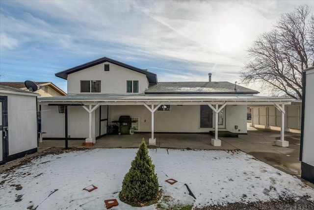 snow covered property featuring stucco siding