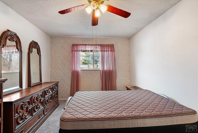 carpeted bedroom featuring a ceiling fan and a textured ceiling