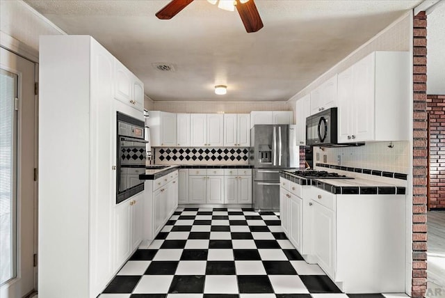 kitchen with stainless steel fridge, tile counters, white cabinets, dark floors, and black microwave