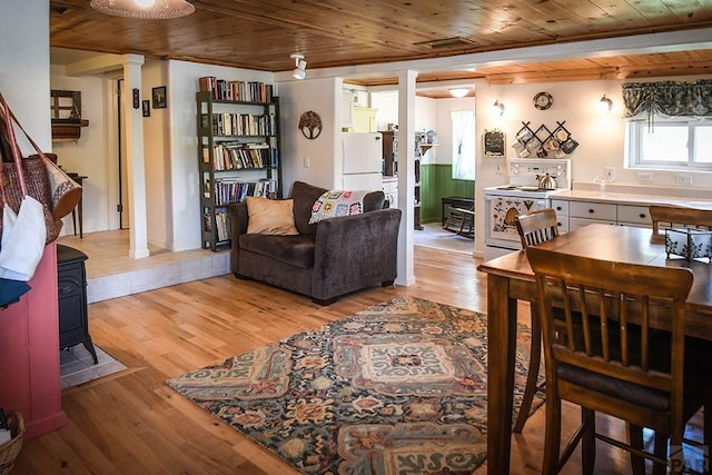 8570 Pine Dr, Beulah, CO 81023 - living room with decorative columns, wooden ceiling, light wood-style floors, and a wood stove