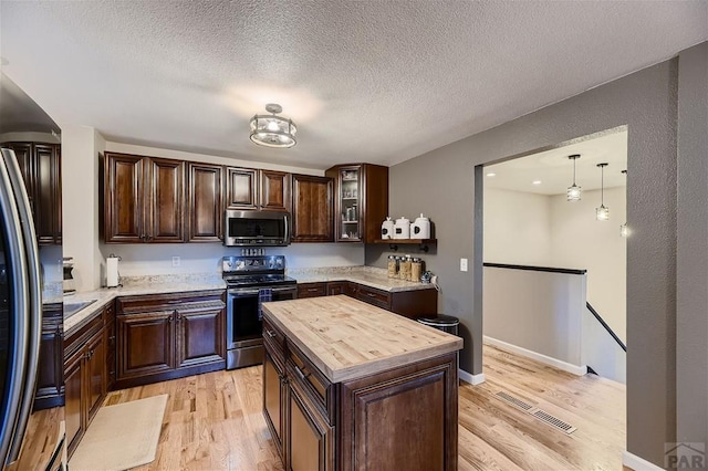 kitchen with visible vents, wooden counters, appliances with stainless steel finishes, dark brown cabinets, and light wood-type flooring