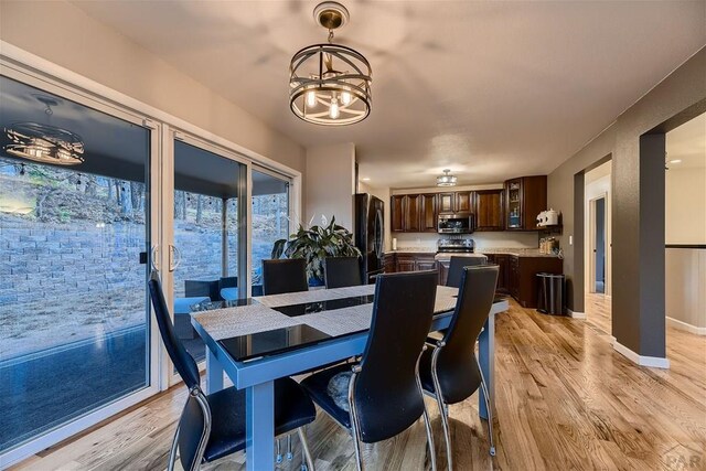 dining space with a chandelier, baseboards, and light wood finished floors