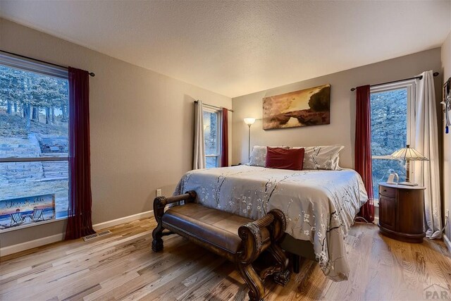 bedroom with light wood-type flooring, visible vents, and baseboards