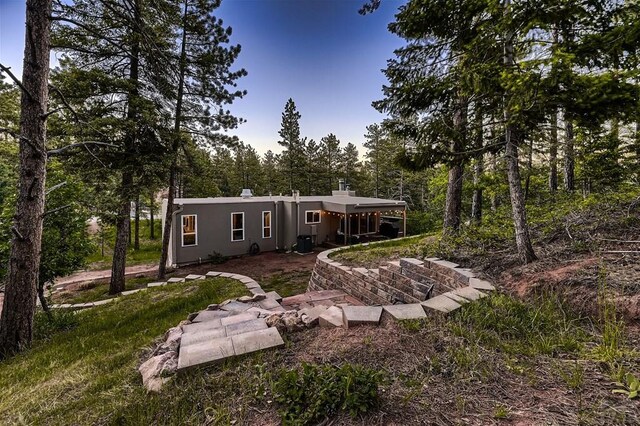 rear view of property with a chimney and stucco siding