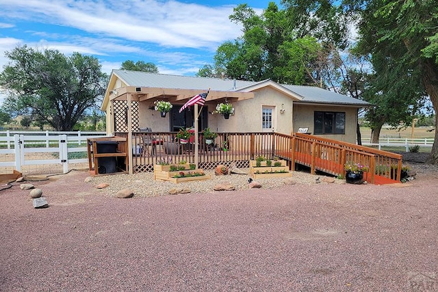 view of front facade featuring a wooden deck, stucco siding, and fence