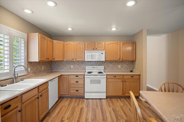 4317 Outlook Blvd Unit D, Pueblo, CO 81008 - kitchen featuring white appliances, a sink, light wood finished floors, light countertops, and backsplash